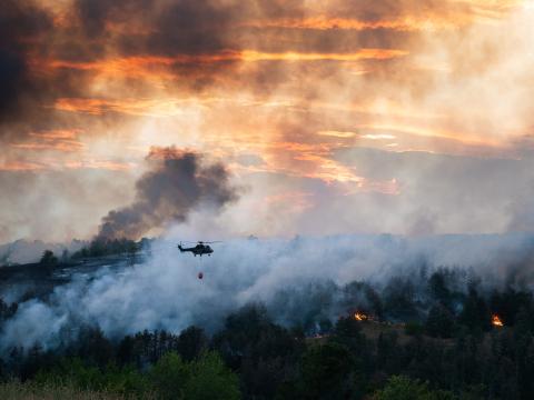 Helicopter flying over a wildfire. 